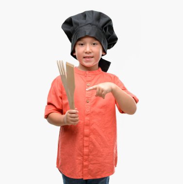 Koyu saçlı küçük çocuk şef üniforması el ve parmak ile işaret çok mutlu