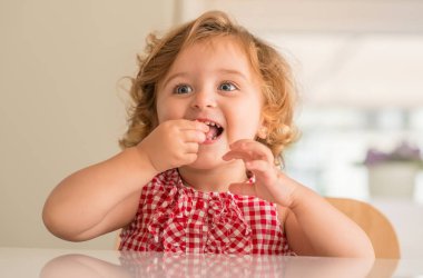Gülümseyen ve şeker evde yemek mavi gözlü güzel sarışın çocuğun.