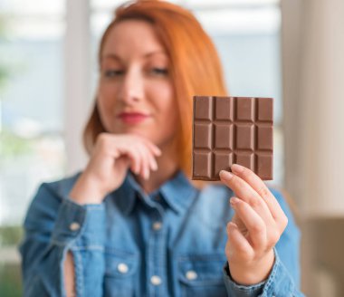 Soru, çok karışık fikir düşünmeye ev ciddi bir yüz, çikolata bar tutan Kızıl saçlı kadın