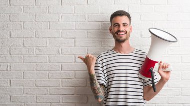 İşaret ve başparmak kadar mutlu yüz gülümseyen tarafı ile gösterilen megafon tutan genç yetişkin adam