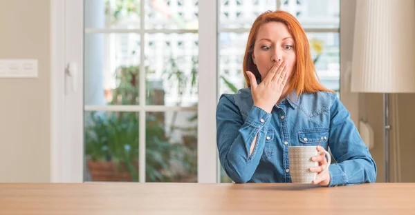 Rødhåret Kvinde Holder Kop Kaffe Dække Mund Med Hånden Chokeret - Stock-foto