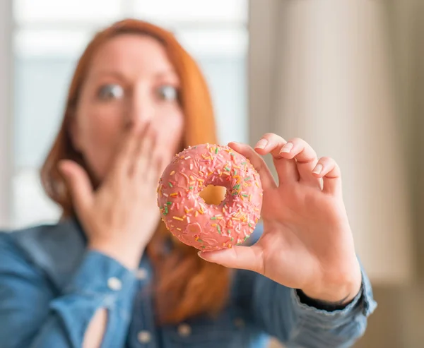 Mulher Ruiva Segurando Donut Casa Cobrir Boca Com Mão Chocada — Fotografia de Stock