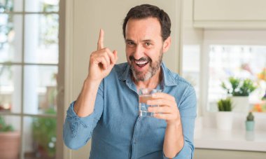 Bir bardak su bir fikirle sürpriz içme yaşı adam orta veya gülen yüz, bir numara ile işaret parmağı soru