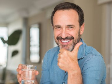 Orta yaş erkek ok işareti, başparmak ile parmak, mükemmel işareti yapıyor kocaman bir gülümseme ile mutlu su içme