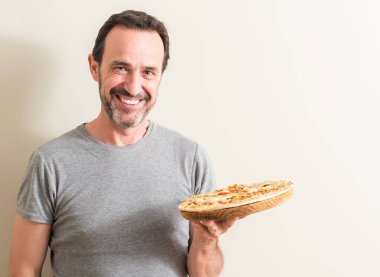 Komuta sizde ayakta ve diş gösterilen kendine güvenen bir gülümsemeyle gülümseyerek mutlu bir yüz ile pizza holding