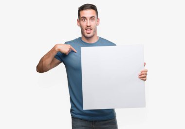 Kendi kendine reklam afişi sürpriz yüz işaret parmağı tutan yakışıklı genç