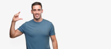 Yakışıklı genç casual adam gülümsüyor ve süre seyir ve kamera boyutu işaret parmaklarıyla yapıyor el ile kendine güvenen el hareketi. Ölçü kavramı.