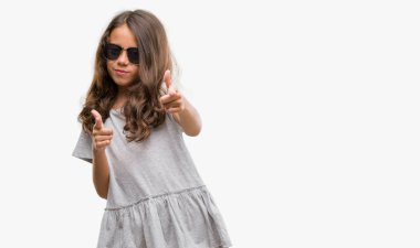 Esmer Latin kız kamera ile mutlu ve komik yüz için parmakları işaret güneş gözlüğü takıyor. İyi enerji ve vibes.