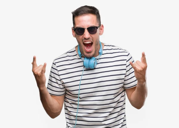 Przystojny Młody Mężczyzna Noszenia Słuchawek Krzycząc Crazy Wyrażenie Robienie Skały — Zdjęcie stockowe