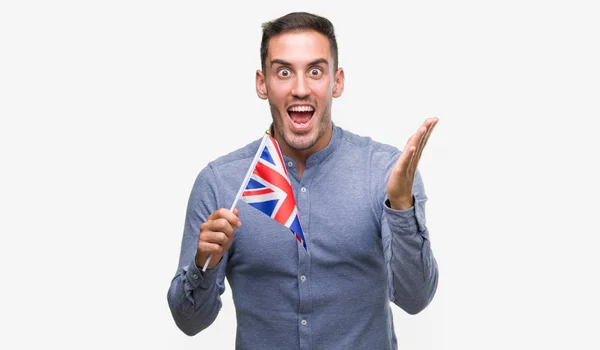 英俊的年轻人拿着英国国旗非常高兴和兴奋 优胜者表达庆祝胜利尖叫与大微笑和举手 — 图库照片