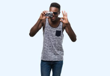 Afro-Amerikan delikanlı vintage kamerayı parmak, mükemmel sembolü ile ok işareti yapıyor