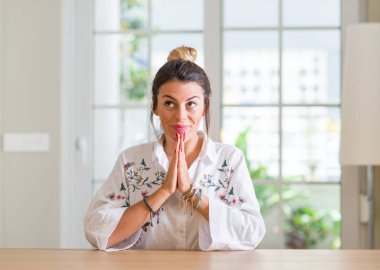 Ellerle birlikte AF emin gülümseyen için soran genç kadın evde dua.