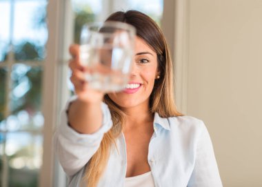 Bir bardak su evde tutarken gülümseyen güzel ve genç birbayan. Yaşam tarzı kavramı.