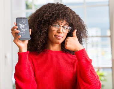 Ok işareti, başparmak ile parmak, mükemmel işareti yapıyor kocaman bir gülümseme ile kırık smartphone mutlu tutan Afrikalı-Amerikalı kadın
