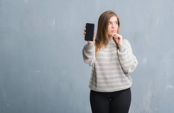 Jonge Volwassen Vrouw Grijs Grunge Muur Weergegeven Leeg Scherm Van — Stockfoto