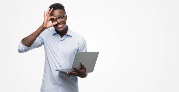 指の間から見て目に手で サインをして笑っている幸せそうな顔でラップトップ コンピューターを使用して若いアフリカ系アメリカ人のビジネスマン — ストック写真