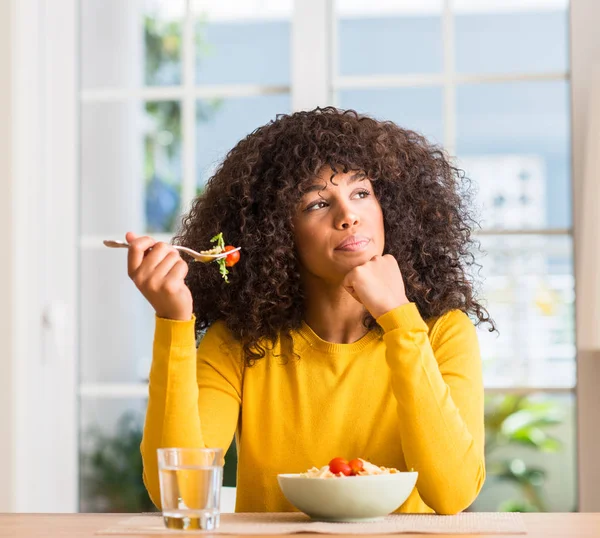 Mujer Afroamericana Comiendo Ensalada Pasta Casa Cara Seria Pensando Pregunta —  Fotos de Stock