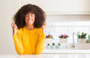 Geçiş parmakları umut ve gözler gülümseyen mutfak at sarı kazak giyen Afrikalı-Amerikalı kadın kapalı. Şans ve batıl kavramı.