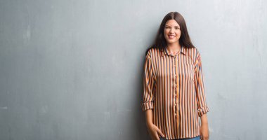 Grunge gri duvar kırpışan kameraya seksi bir ifadeyle, neşeli ve mutlu yüz seyir üzerinde genç esmer kadın.