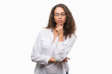 Güzel genç İspanyol kadın emin çapraz kollar ve çeneme kaldırdı el ile gülümseme ile kameraya bakıyor. Pozitif düşünce.