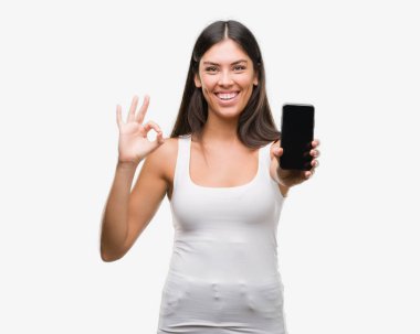 Genç güzel İspanyol gösteren smartphone parmak, mükemmel sembolü ile ok işareti yapıyor