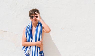 Tatil günlerinde mutlu yüz el parmaklarının arasından seyir göz üzerinde ok işaretiyle yapıyor gülümseyen bir donanma havlu giyen genç çocuk