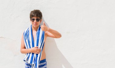 Tatil günlerinde ok işareti, başparmak ile parmak, mükemmel işareti yapıyor kocaman bir gülümseme ile mutlu bir donanma havlu giyen genç çocuk