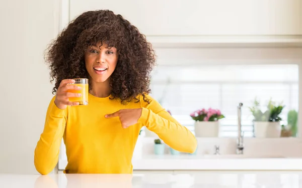 Afroamerikanerin Trinkt Orangensaft Einem Glas Mit Überraschungsgesicht Und Zeigt Mit — Stockfoto