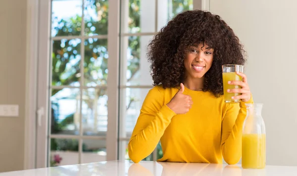 非洲裔美国妇女在家里喝健康的果汁开心的笑着做 拇指用手指 优秀的标志 — 图库照片