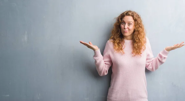 Young Redhead Woman Grey Grunge Wall Wearing Pink Sweater Clueless — Stock Photo, Image