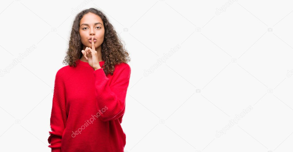 Young hispanic woman wearing red sweater asking to be quiet with finger on lips. Silence and secret concept.