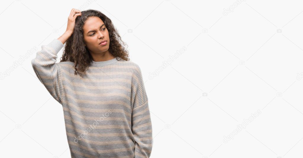 Beautiful young hispanic woman wearing stripes sweater confuse and wonder about question. Uncertain with doubt, thinking with hand on head. Pensive concept.