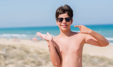 Sahilde el ve parmak ile işaret çok mutlu tatil günlerinde genç çocuk