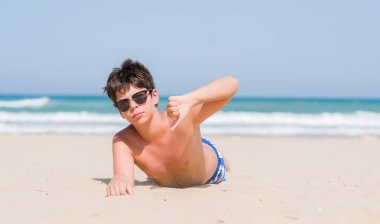 Kızgın yüz, eksi işareti aşağı antipati başparmak ile gösterilen, ret kavramı ile sahilde tatil günlerinde genç çocuk