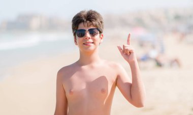 Plajda bir fikir ya da soru işaret parmağı ile gülen yüz, sürpriz tatil günlerinde genç çocuk bir numara