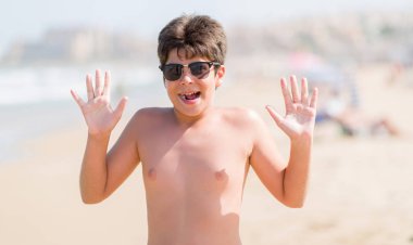 Kocaman bir gülümseme ile çığlık zaferini kutluyor ve ellerini kaldırdı beach çok mutlu ve heyecanlı, kazanan ifade, tatil günlerinde genç çocuk