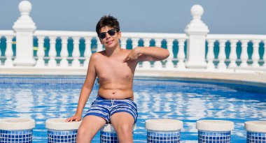 Kendisi için sürpriz yüz işaret parmağı plajda yüzme havuzunda genç çocuk tatilde