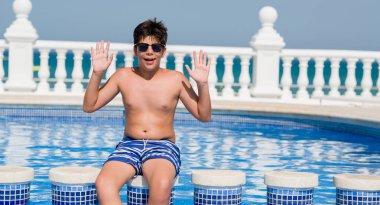 Kocaman bir gülümseme ile çığlık zaferini kutluyor ve ellerini kaldırdı beach çok mutlu ve heyecanlı, kazanan ifade tarafından yüzme havuzunda genç çocuk tatilde