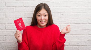 Gurur çığlık ve zafer ve başarı çok heyecanlı, duygu tezahürat kutluyor Genç Çinli kadın pasaport Japonya tutan tuğla duvarın üzerinden