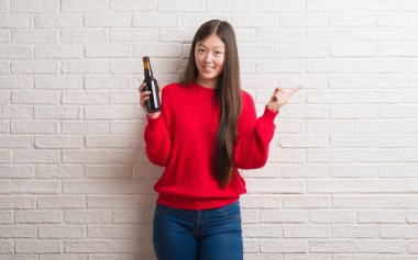 Genç Çinli kadın dilini beyaz tuğla duvarın üzerinden out komik ifade ile mutlu. Duygu kavramı.