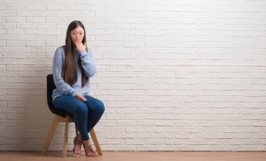 Genç Çinli kadın dilini beyaz tuğla duvarın üzerinden out komik ifade ile mutlu. Duygu kavramı.