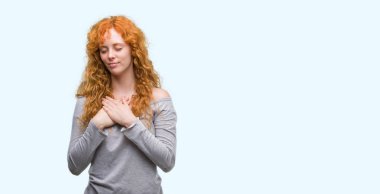 Göğüs kapalı gözlerle ellerinde ve yüzünde minnettar jest ile gülümseyen genç Kızıl saçlı kadın. Sağlık kavramı.