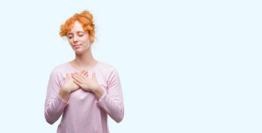 Göğüs kapalı gözlerle ellerinde ve yüzünde minnettar jest ile gülümseyen genç Kızıl saçlı kadın. Sağlık kavramı.
