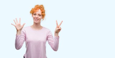 Gösterilen ve parmakları ile işaret genç Kızıl saçlı kadın kendinden emin ve mutlu gülümseyerek süre yedi numara.