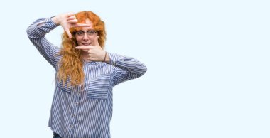 Elle yapma çerçeve ve parmakları ile mutlu yüz gülümseyen genç redhead bussines kadın. Yaratıcılık ve Fotoğrafçılık kavramı.