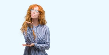 Genç redhead bussines kadın bir öpücük el ile güzel ve seksi olmak hava üfleme kamera bakıyor. Aşk ifade.