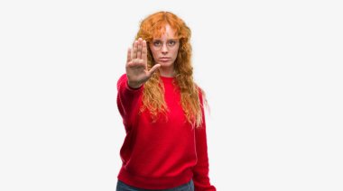 Kırmızı kazaklı elin avuç durağı şarkı yapıyor giyen genç Kızıl saçlı kadın. Negatif ve ciddi bir jest yüz ifadesiyle uyarı.