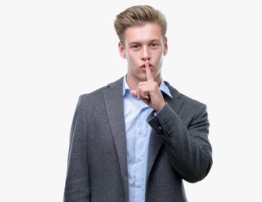 Genç yakışıklı sarışın iş adamı dudaklarında parmak ile sessiz olmanı. Sessizlik ve gizli kavramı.