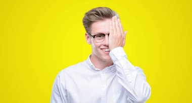 Genç yakışıklı sarışın adam yüz ve sürpriz duygu kendinden emin gülümseme ile el ile bir göz kapsayan.