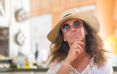 Tatil ciddi bir yüz düşünme hakkında soru, çok karışık fikir orta yaş esmer kadın giyiyor yaz şapka